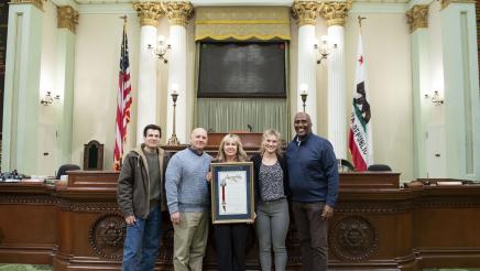 Assemblymember Cooper, Jennifer Freeworth and her family with her retirement resolution on the Assembly Floor
